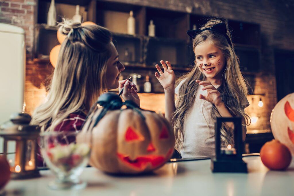 Photo of a mother puting halloween makeup on her daughter