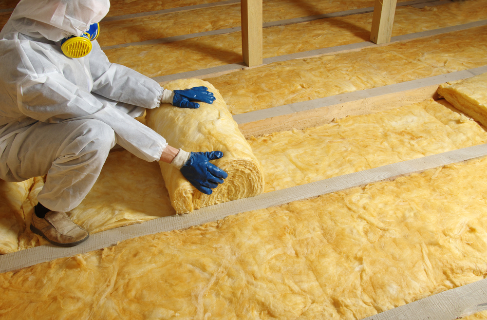 Tech installing fiberglass insulation rolls