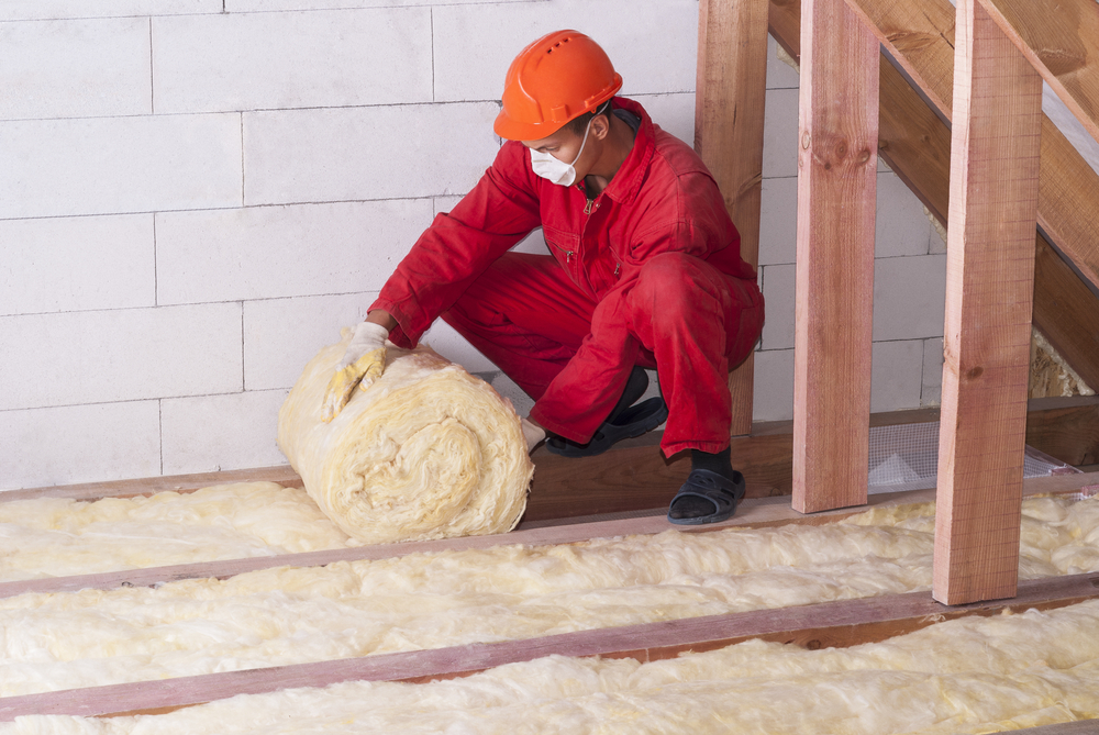 Technician rolling out attic insulation