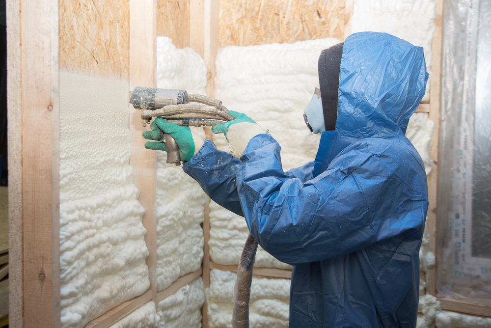 Attic Man worker spraying foam insulation and how it can help with temperature control